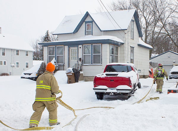 Albert Lea Fire Department firefighters bring a water hose into a house at 1019 James Ave. to fight a fire that reportedly started in the attic. - Sam Wilmes/Albert Lea Tribune