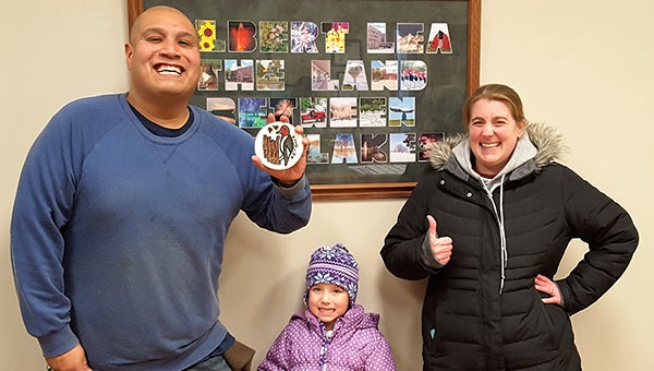 From left, Danny, Renee and Brooklyn Martinez found The Big Freeze medallion Wednesday afternoon in a flower pot in downtown Albert Lea, in a flower pot on the corner of Clark Street and Broadway in front of the former Alliant Energy building. — Provided