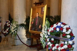 Flowers given by the U.S. House of Representatives and the Senate on Friday sit near a painting of the late Supreme Court Justice Antonin Scalia in The Great Hall of the Supreme Court. -Provided