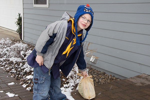 Blake Redmond of Cub Scouts Pack 105 collects a donation bag in southwest Albert Lea during the 2016 Scouting for Food event on Saturday. - Amy Gauthier/For the Albert Lea Tribune