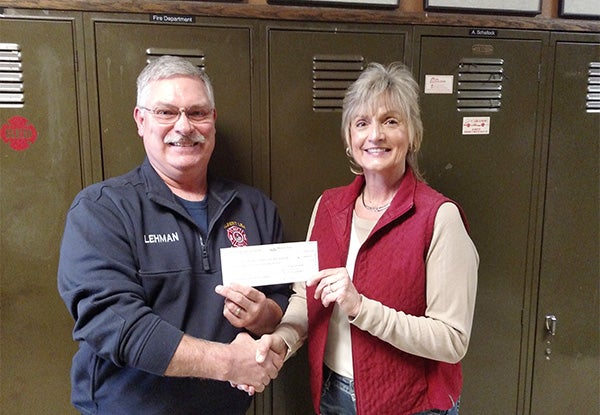 Bill Lehman, secretary/treasurer of the Albert Lea Professional Firefighters, accepts a donation from Jody Adams of the Maple Island Park Association. The contribution will help fund the 25th annual firstgrade fire education/T-shirt program conducted each year by the firefighters. During the first week of May, all the first-graders in Albert Lea School District No. 241, Hollandale Christian School and home school receive a cartoon/fire-themed T-shirt for learning fire safety. -Provided