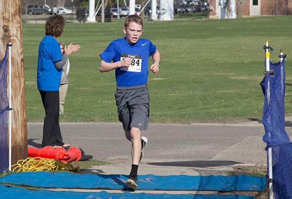 Cameron Davis, 12, crosses the finish line of the Southwest Middle School Tiger Trot Saturday morning in front of Brookside Education Center. Davis was the first to finish the race. - Sarah Stultz/Albert Lea Tribune