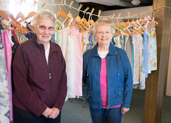 Karnella Schwierjohann, left, and Judy Luksik stand with the pillowcase dresses the women at Glenville United Methodist Church made that will be sent to young girls in Africa. - Sarah Stultz/Albert Lea Tribune