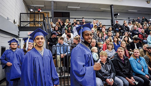 Anderson Gois Siqueira, right, and Jorman A. Calle De Oliveira lead the first group of graduates into the Riverland Community College gym Friday afternoon in Austin. - Eric Johnson/Albert Lea Tribune