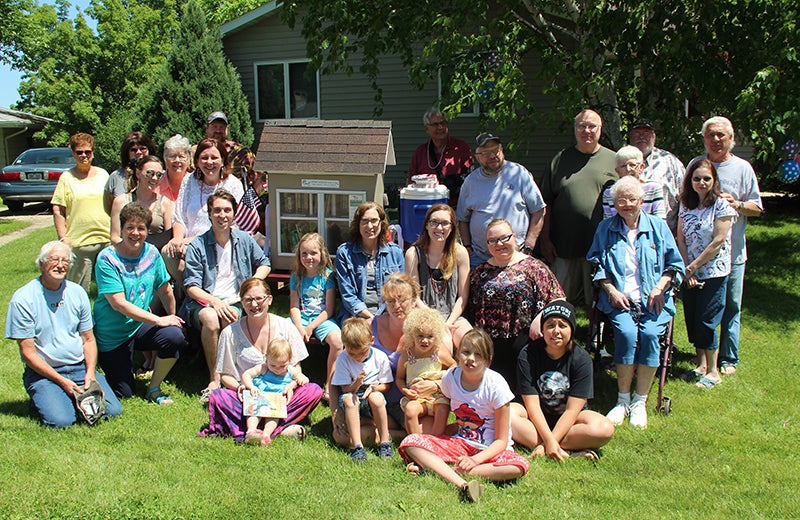 People attending a dedication ceremony for a new Little Free Library, outside the home of Mike and Renee Lee, 2141 Kenneth Drive, pose for a photo Monday afternoon. The Little Free Library aims to promote literacy and a love of reading by building free book exchanges. It is the third such location in Albert Lea. Renee Lee said it was built in memory of Gary Turnmire, who helped her build the original structure, which started out as a dollhouse several years ago. It has since been transformed for the Little Free Library.  - Sarah Stultz/Albert Lea Tribune