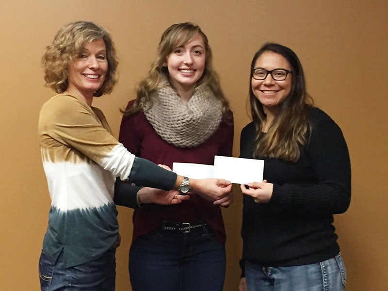 Riley Schulz and Kaitlyn Larson accept scholarships after finishing their first semester of college.  Rotary President Sheila Schulz presented each girl with a $500 check. Schulz goes to the University of Minnesota and Larson attends Ohio State. - Provided