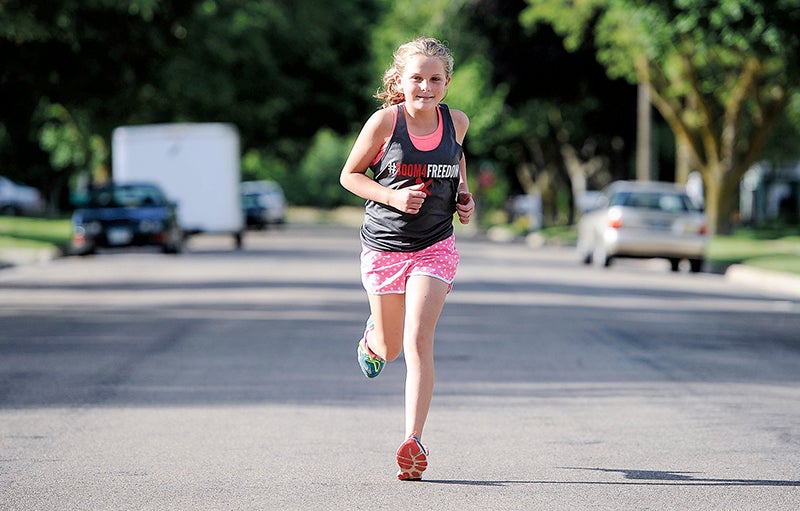 Julie Nesvold, 11, runs down the street past her house Friday night. The daughter of Kelly Nesvold will run with her father during a fundraising triathlon later this summer. - Eric Johnson/Albert Lea Tribune
