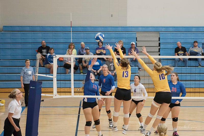 Lake Mills volleyball players Hailey Borgmeyer (13) and Lexi Groe jumped to attempt to block a kill attempt by Northwood-Kensett’s Miranda Stambaugh during the two team’s tournament at Central Springs Saturday. Lory Groe/For the Albert Lea Tribune