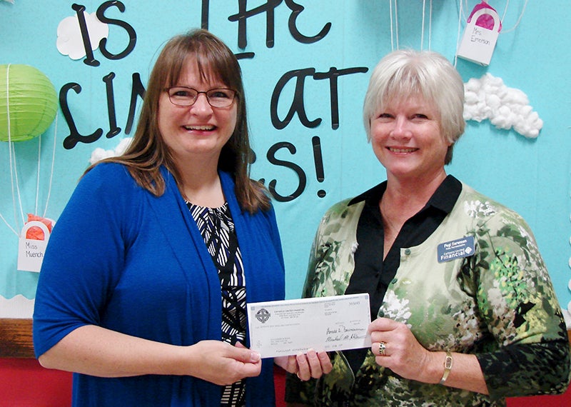 St. Casimir’s School Principal Joanne Tibodeau accepts a dontion to the school from Pegi Sorenson, a representative of Catholic United Financial. - Provided