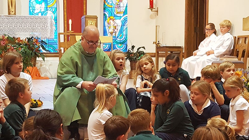 The Rev. Russ Scepaniak sits down with the St. Theodore students at each children’s Mass. He reads the gospel and then  teaches a lesson that helps the students understand what the readings are about. - Provided