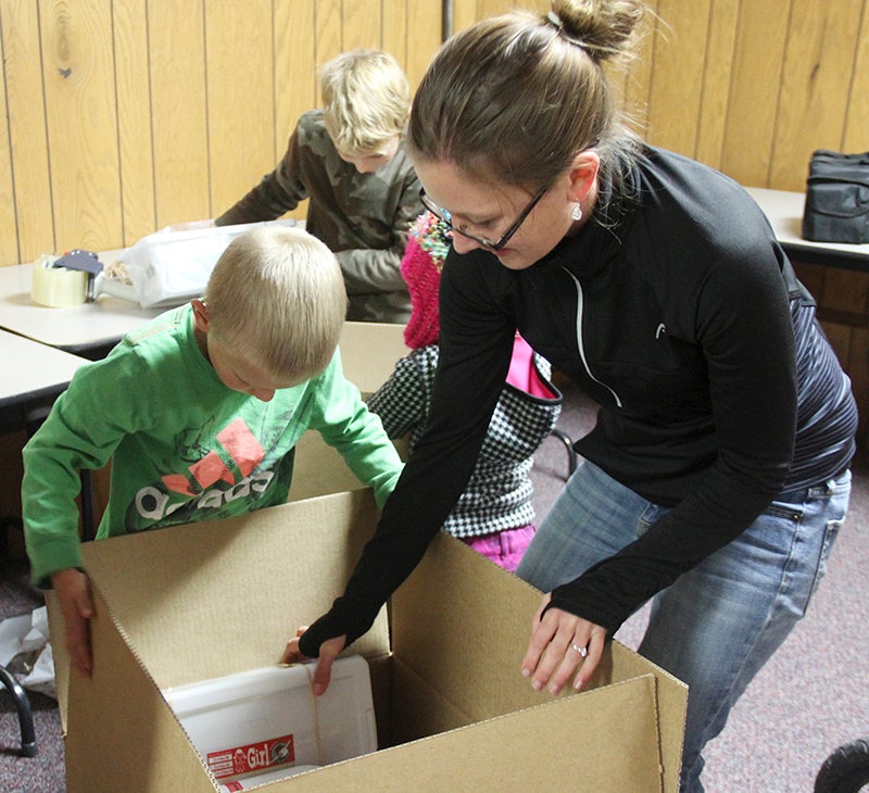 Jodi Hartman and her son Titus, 6, pack boxes for Operation Christmas Child at Bridge Community Church on Monday. The church opened for donations for the program. - Sarah Stultz/Albert Lea Tribune