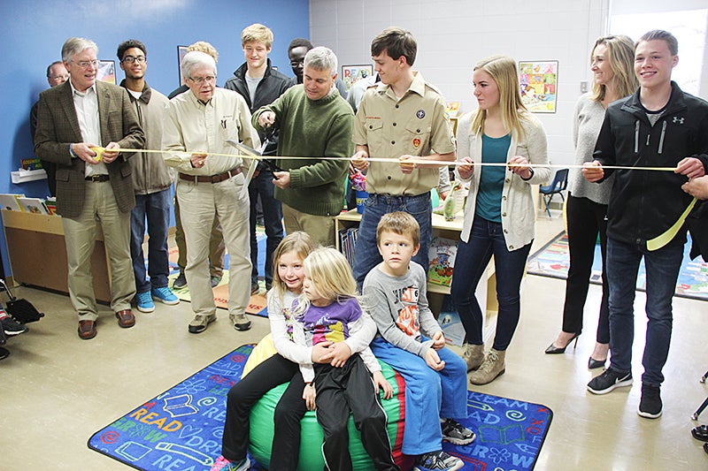 Albert Lea Area Schools Superintendent Mike Funk on Friday cuts a ribbon for the grand opening of the Reading Oasis Library at Brookside Education Center, surrounded by others who were a part of the project. Sarah Stultz/Albert Lea Tribune